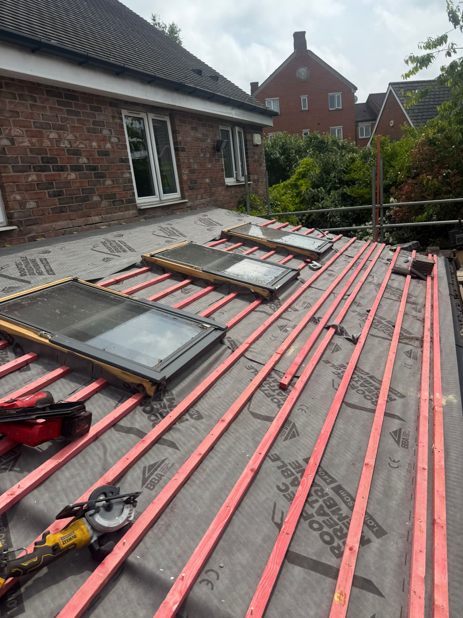 Roof underlay and red battens around two roof windows on a brick house.