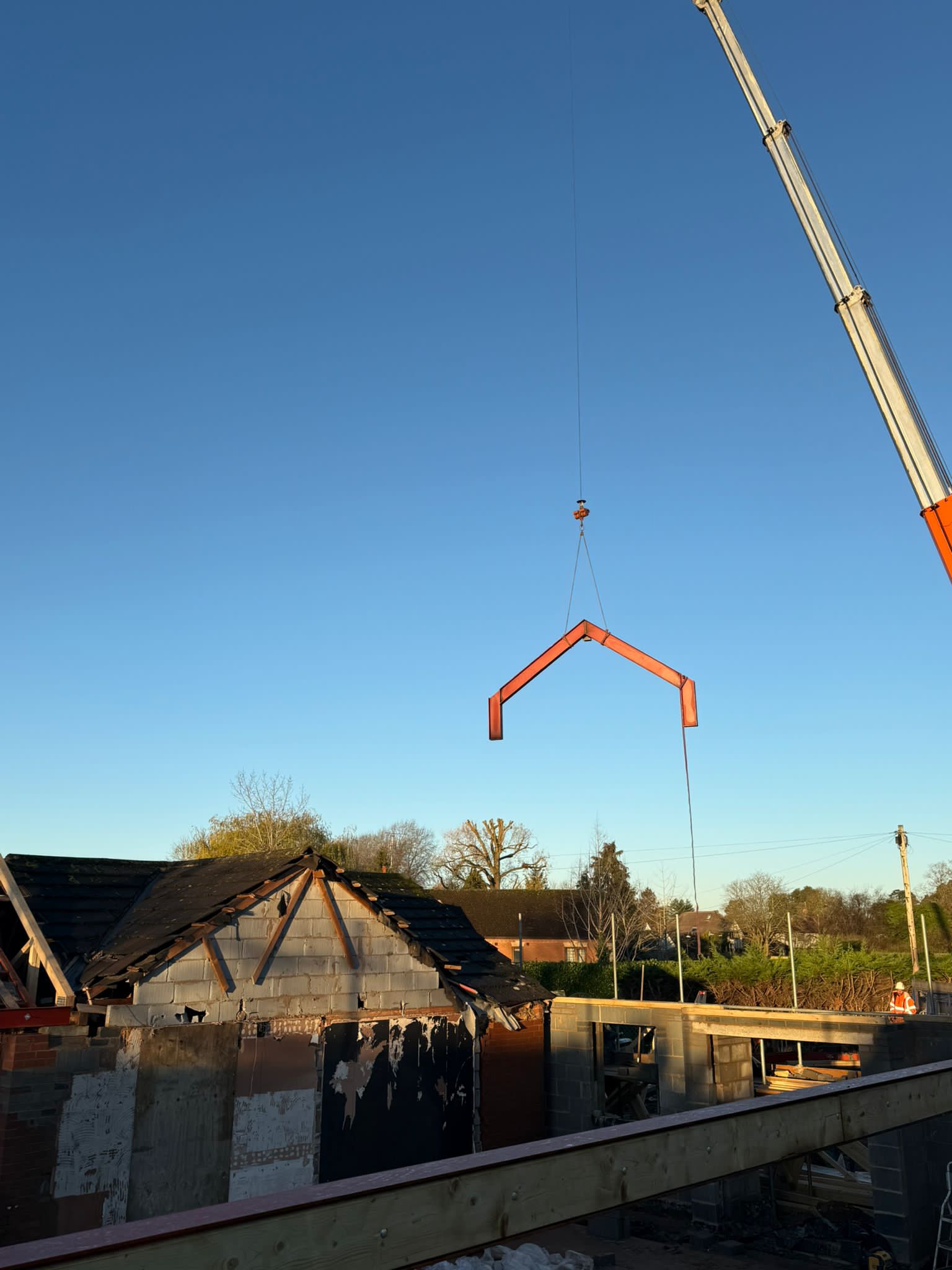 Crane lifting roof structure materials above a building frame.