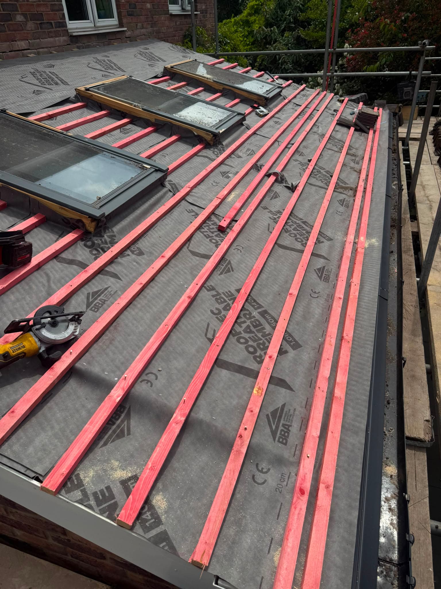 Reroof in progress in Dickens Heath, with grey breather membrane and treated battens laid across the roof and roof windows set in.