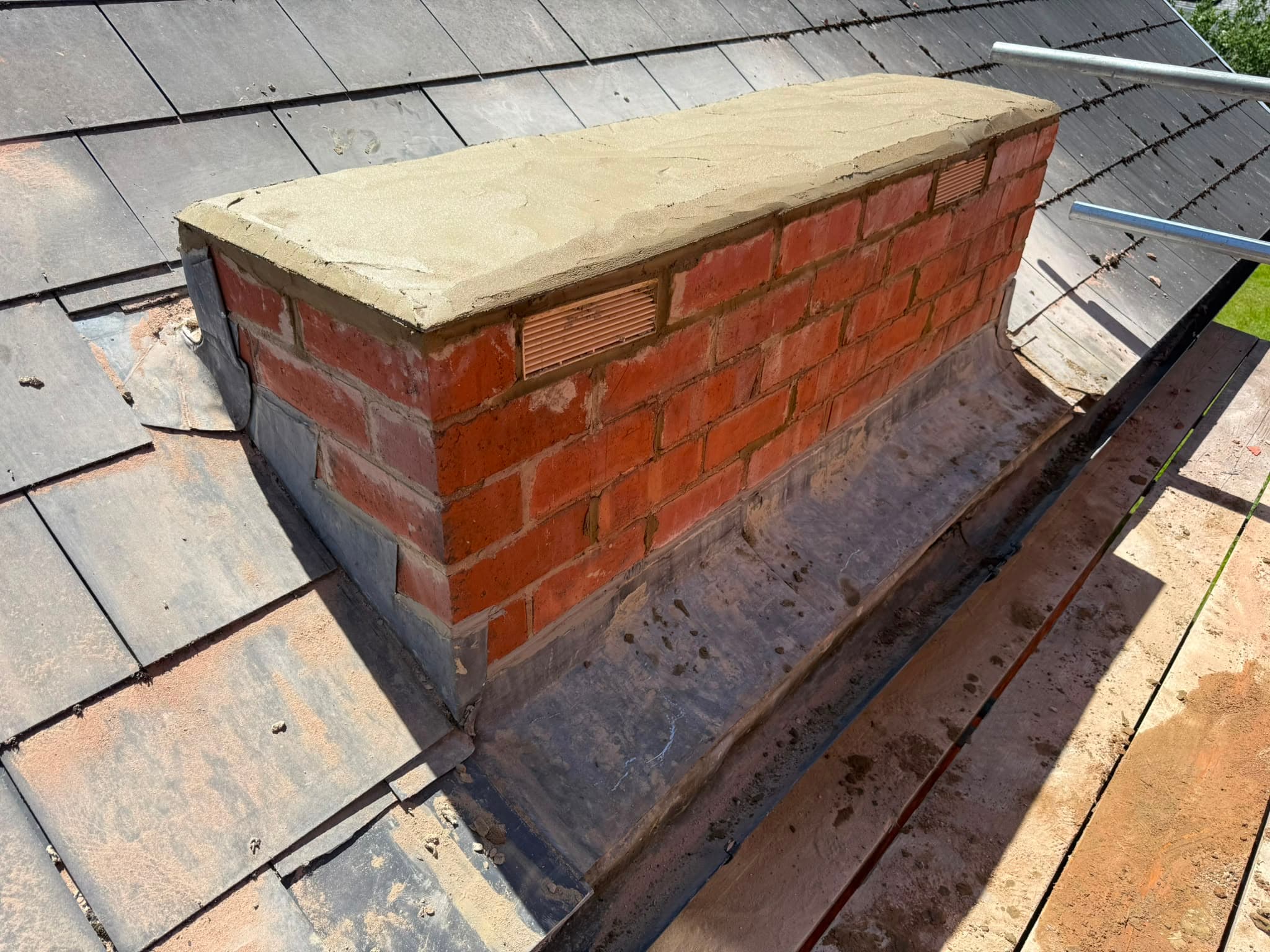 Reduced red-brick chimney rebuilt and capped off with a mortar cap, air vents and new lead flashing dressed to the roof.
