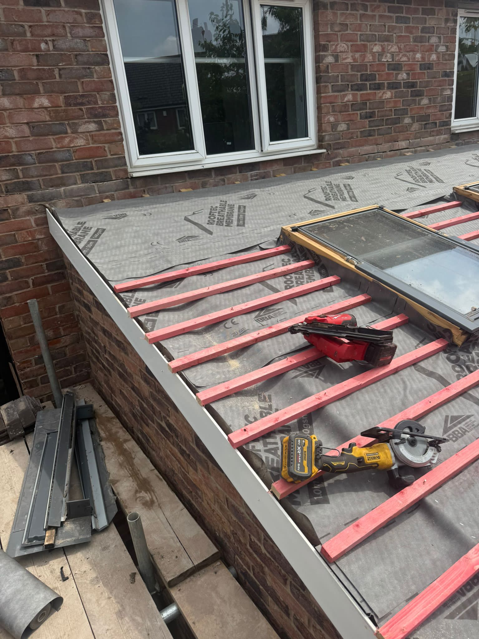 Roof edge and guttering detail on a brick house re-roof, tools laid out on the breather membrane.